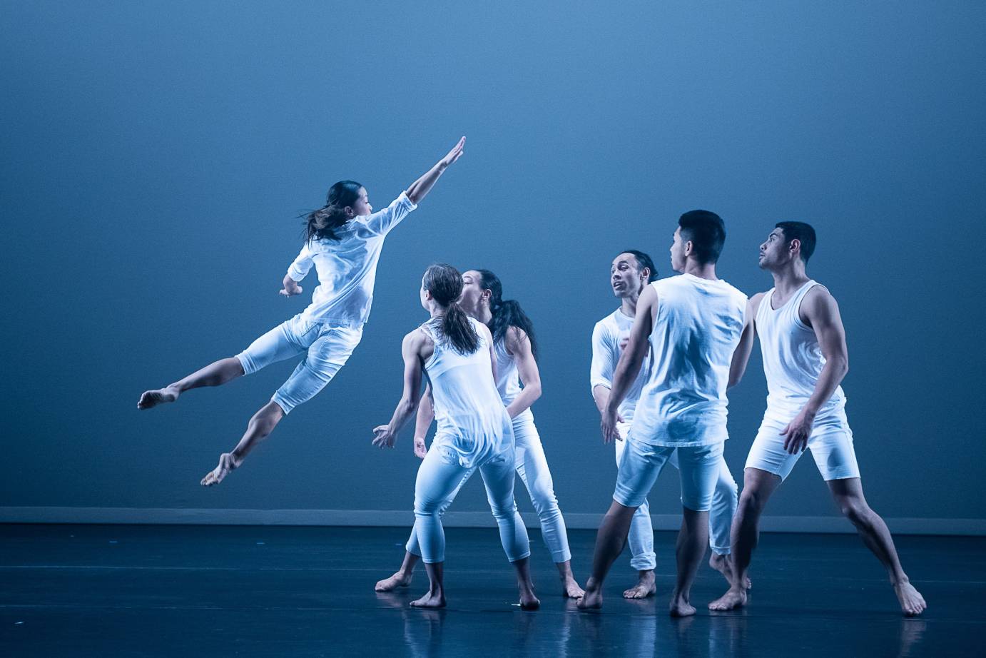 One woman dives into a group of dancers; everyone is in white